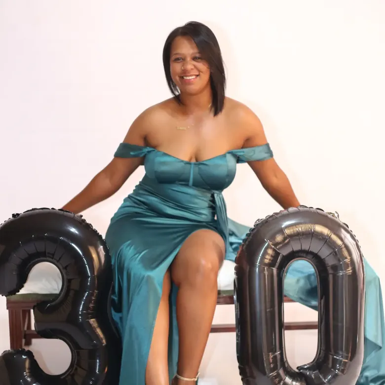 Milestone birthday session, client in an emerald satin gown seated with gold thirty balloons