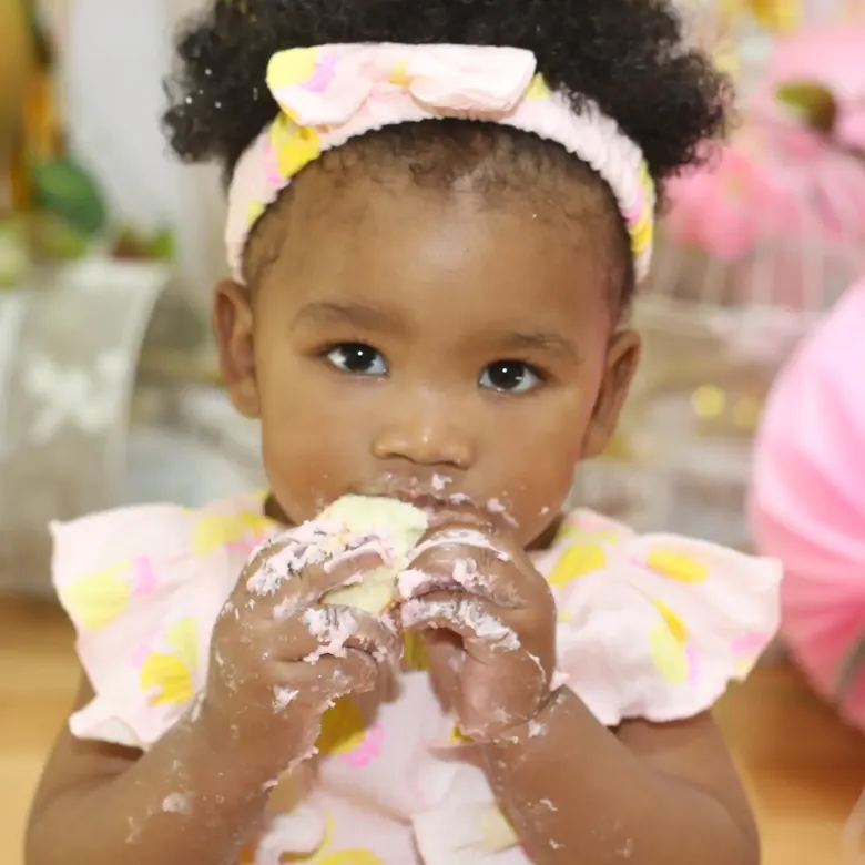 Cake-smash session, a baby girl with icing on her hands during her first birthday shoot
