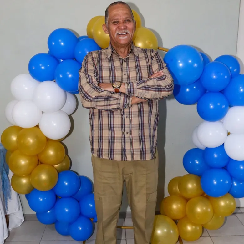70th birthday portrait, guest of honour in front of a blue and gold balloon arch