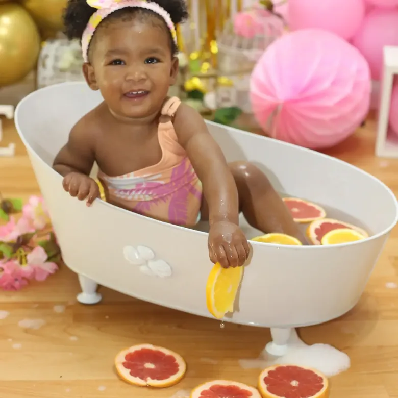 First birthday milk-bath session, a baby girl in a tub with citrus slices