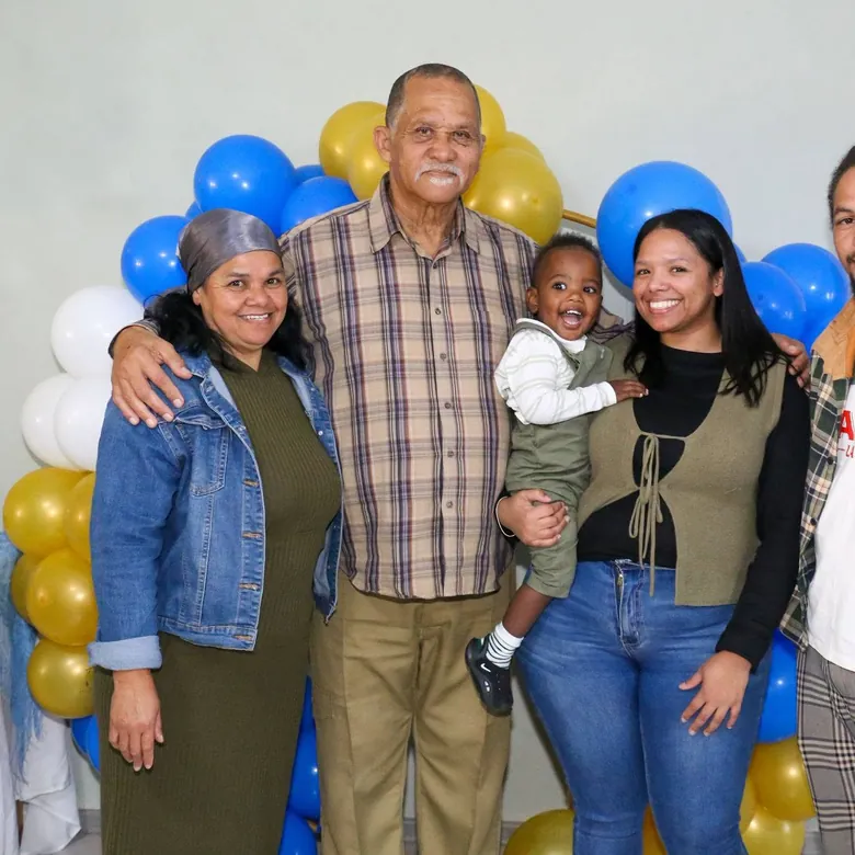70th birthday family portrait in front of a blue and gold balloon arch