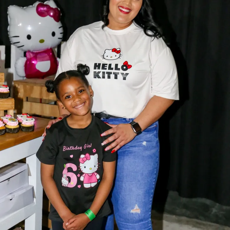 Sixth birthday party, the birthday girl with her mom by a Hello Kitty dessert table