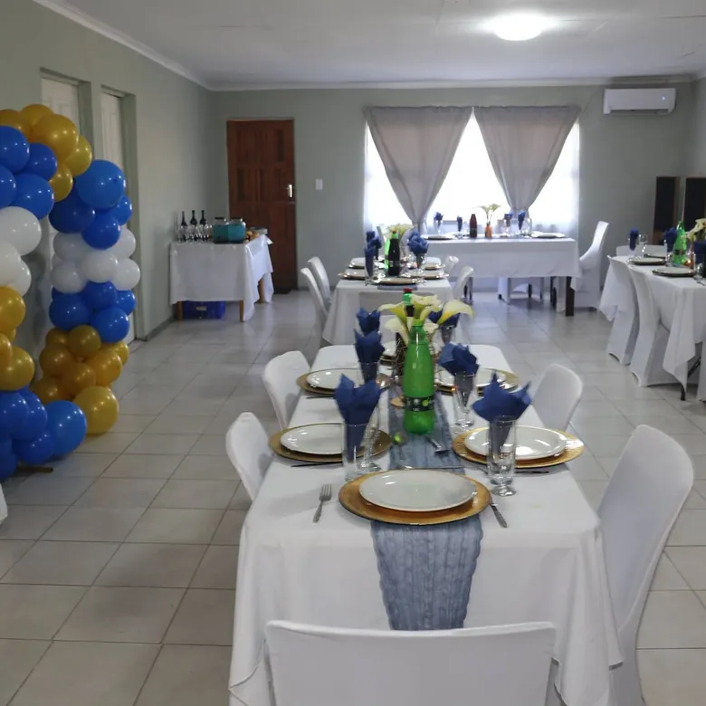 70th birthday venue set-up, tables in white with blue and gold balloon styling