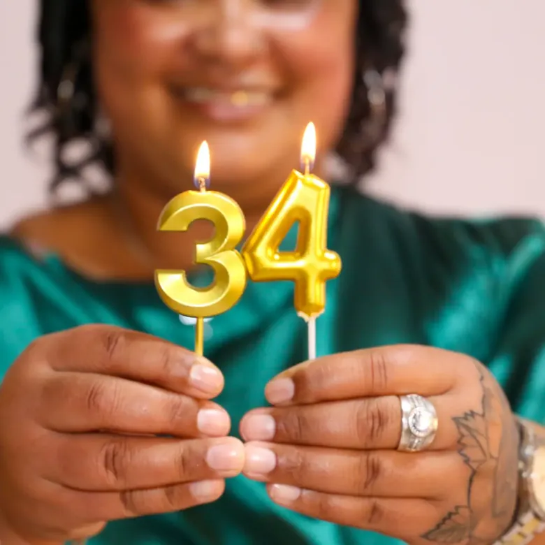 Milestone birthday session, hands holding gold number thirty-four candles