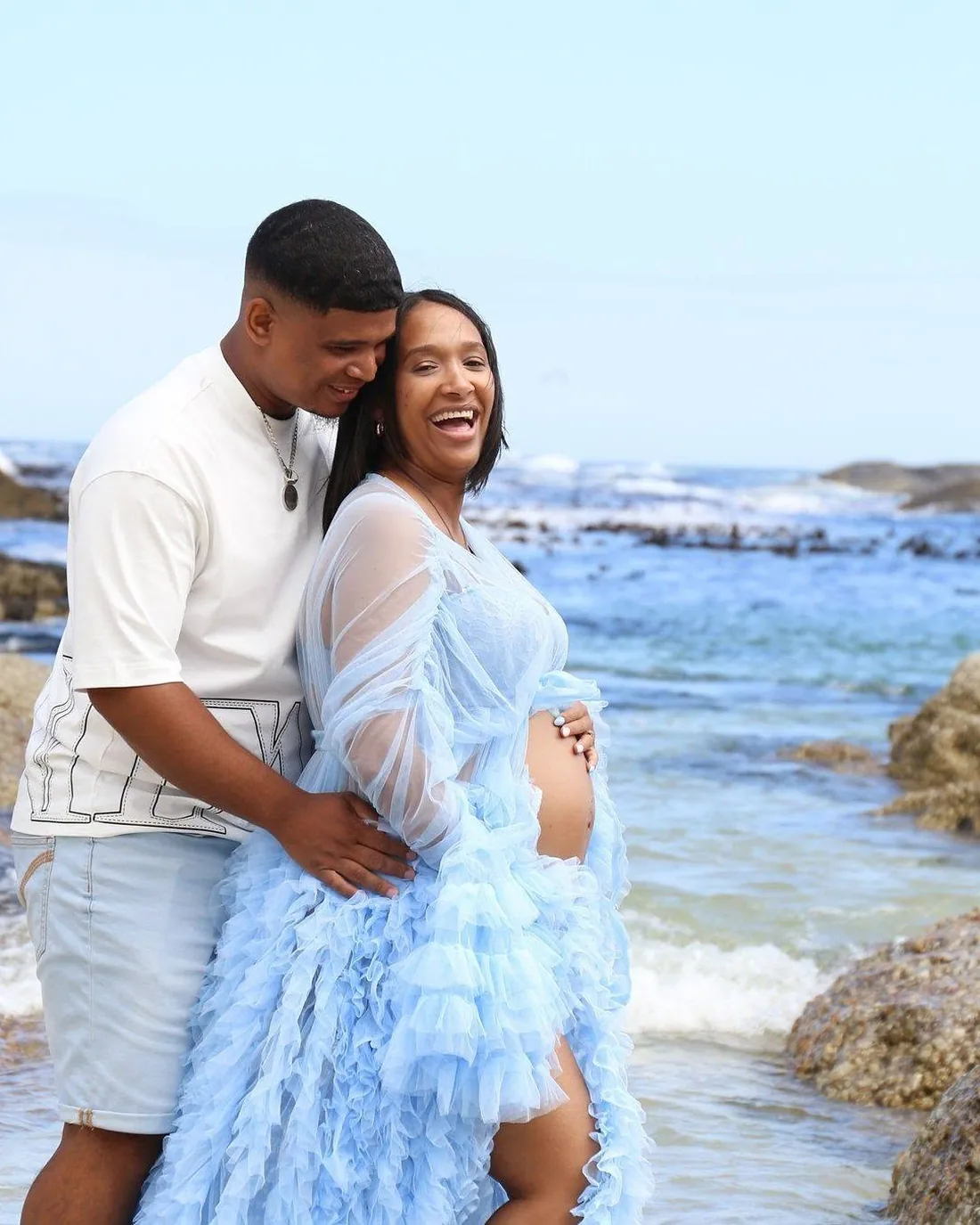 Maternity session on a Cape Town beach, expecting couple embracing, mother in a pale blue tulle gown